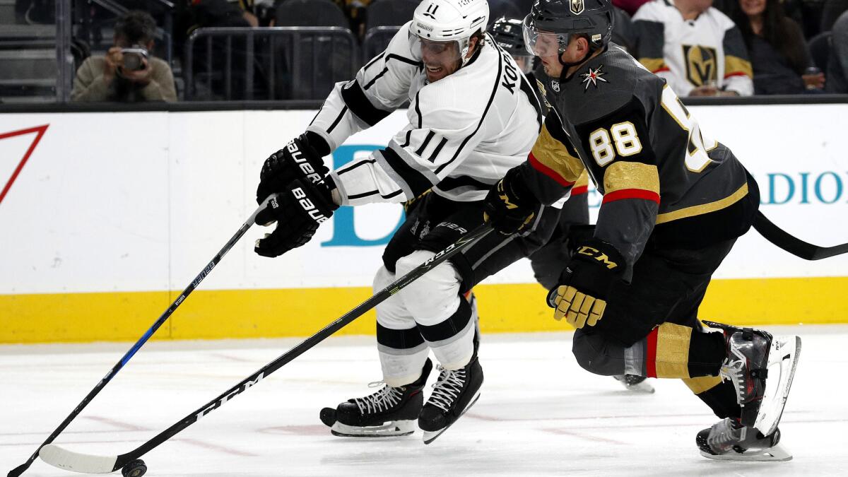 Kings center Anze Kopitar (11) tries to skate around Knights defenseman Nate Schmidt during the third period Sunday.