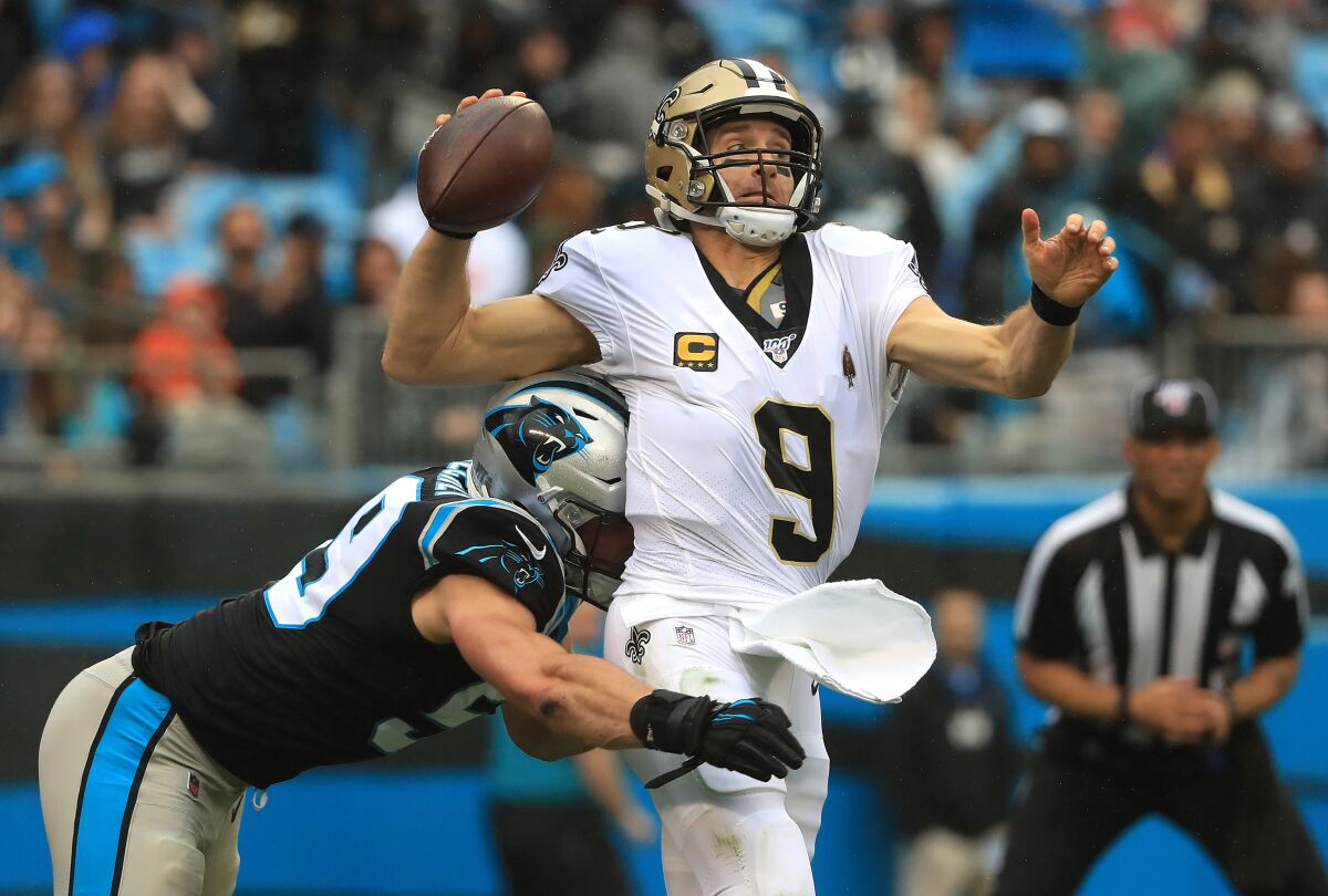 New Orleans Saints quarterback Drew Brees is hit by Carolina Panthers linebacker Luke Kuechly as he throws.