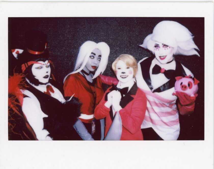 Four people cosplaying with white faces and red and black costumes.