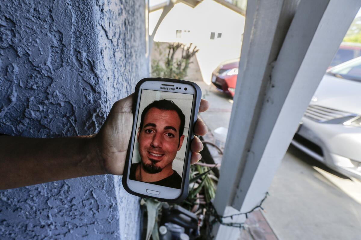 Next-door neighbor Maria Gomez holds her phone displaying a photo of Amir Issa, who police say was killed by his father.