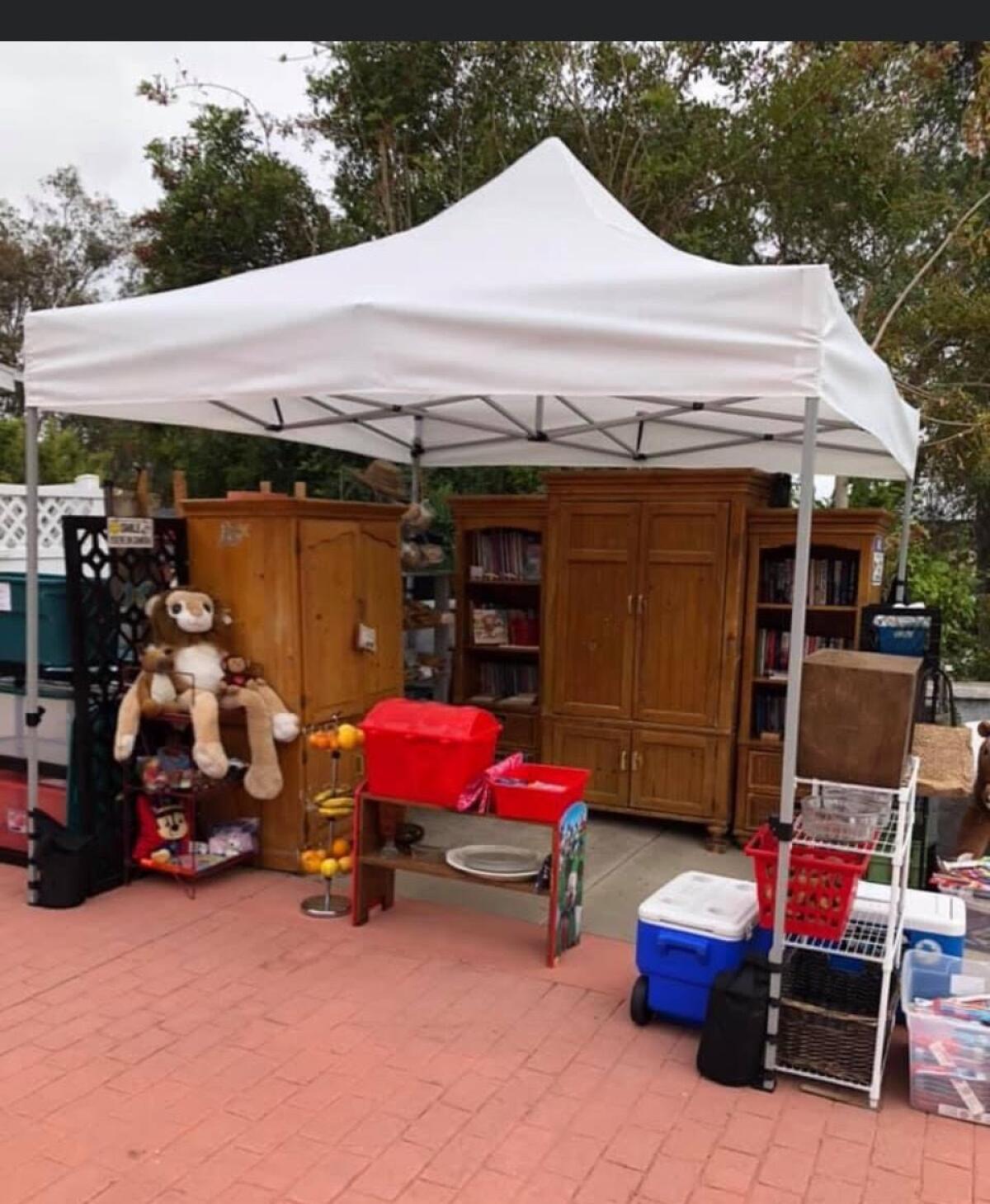 A white tent covers furniture, stuffed animals and food items