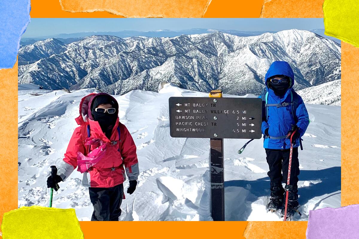 Youngsters in winter coats and balaclavas stand in snow at a trail sign.