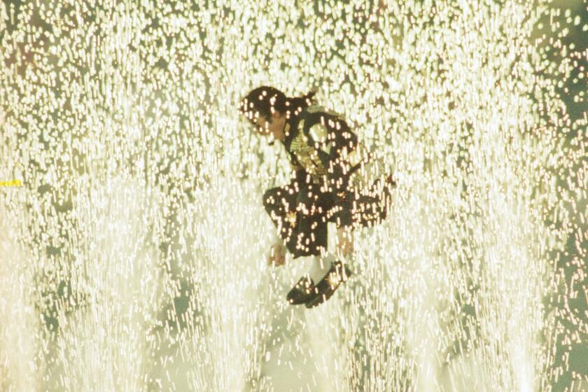 Entertainer Michael Jackson leaps among the pyrotechnics during the halftime show at Super Bowl XXVII in Pasadena, Sunday, Feb. 1, 1993. (AP Photo/Douglas Pizac)