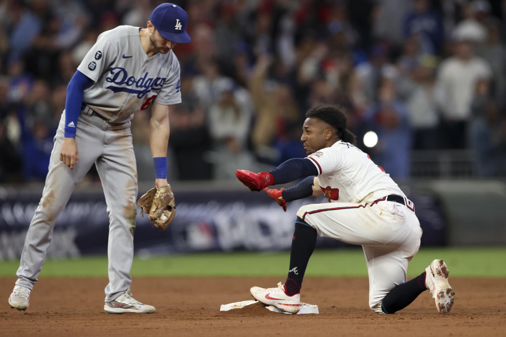 Braves' Ozzie Albies, right, reacts after stealing second past Dodgers second baseman Trea Turner