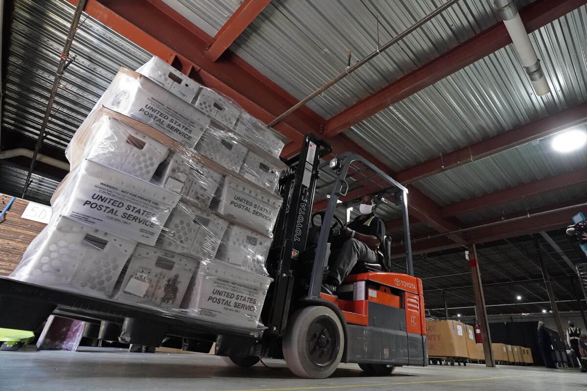 A forklift driver moves pallets of boxes of absentee ballots for mailing at a North Carolina U.S. Postal Service warehouse.