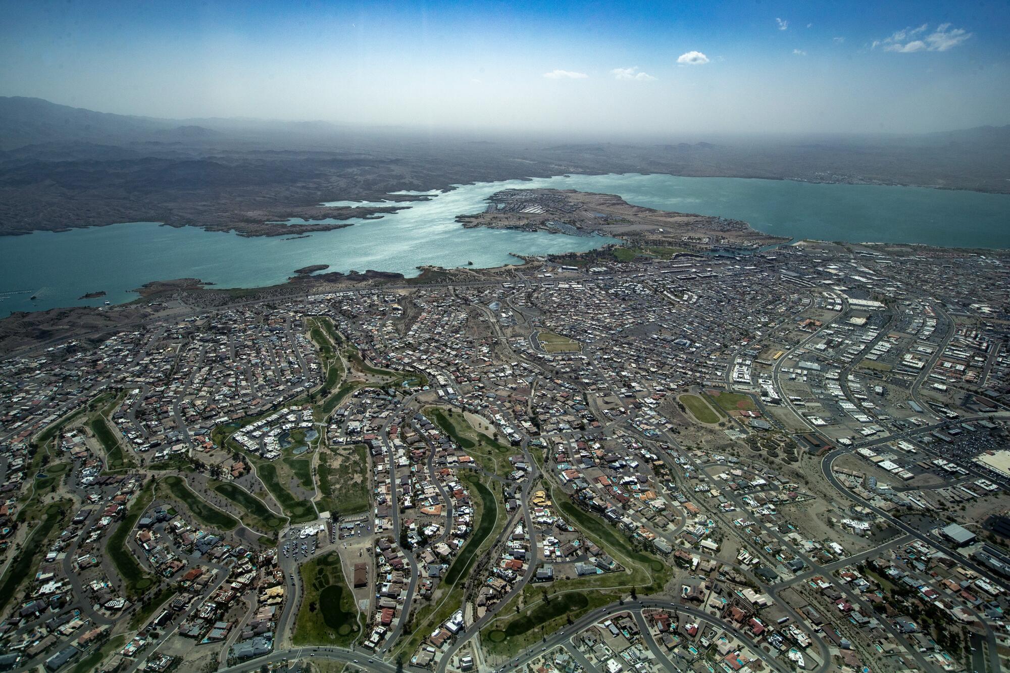 Sunlight glints off a river behind a sprawling desert city.