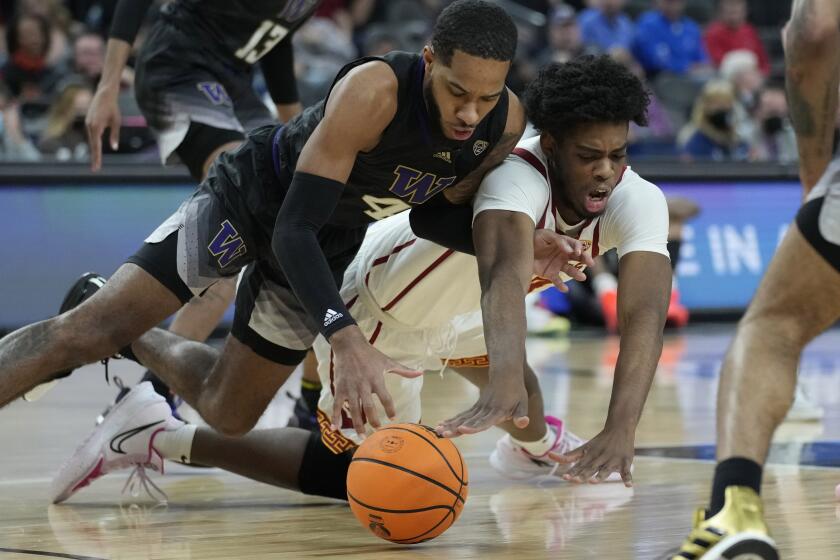 Washington's PJ Fuller, left, and Southern California's Joshua Morgan (24) scramble for the ball during the first half of an NCAA college basketball game in the quarterfinal round of the Pac-12 tournament Thursday, March 10, 2022, in Las Vegas. (AP Photo/John Locher)