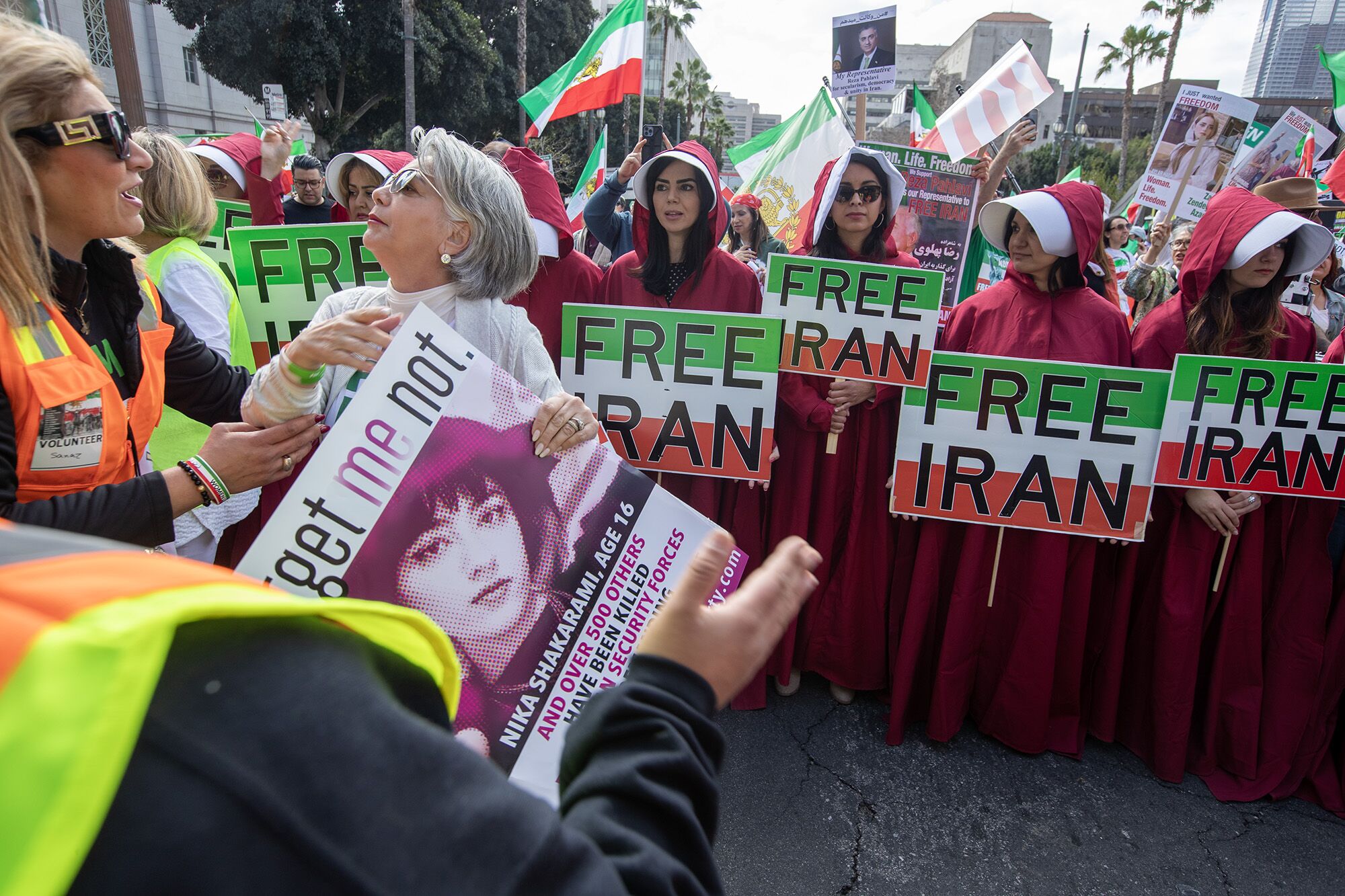 People dressed as characters from "The Handmaid's Tale" hold signs saying "Free Iran"