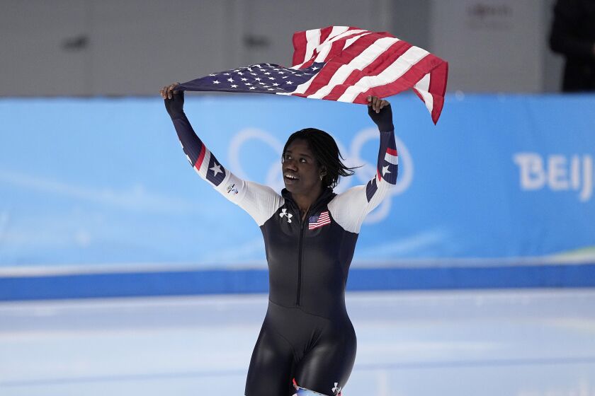 Erin Jackson of the United States hoists an American flag after winning the gold medal in the speedskating women's 500-meter race at the 2022 Winter Olympics, Sunday, Feb. 13, 2022, in Beijing. (AP Photo/Sue Ogrocki)