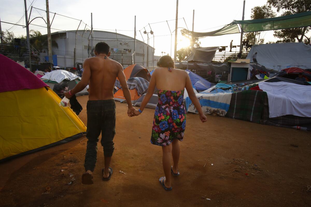 After bathing at the open showers, Nelson Ruiz and his wife Damari Alejandra Tajeda walk back to their tent in wet clothes. The young couple from Honduras arrived in Tijuana with Central American migrant caravan.