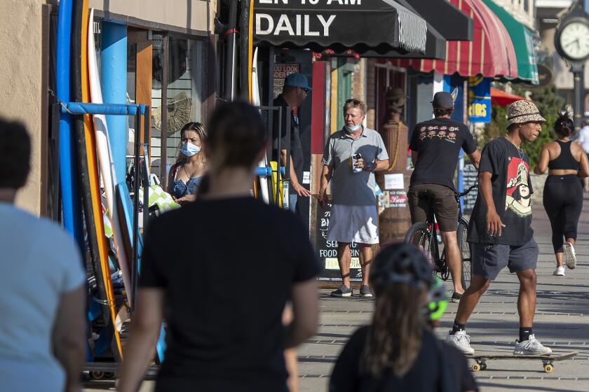 NEWPORT BEACH, CA - JULY 20: People walk and skateboard on the sidewalk past businesses on a summer day Monday, July 20, 2020 in Newport Beach, CA. (Allen J. Schaben / Los Angeles Times)