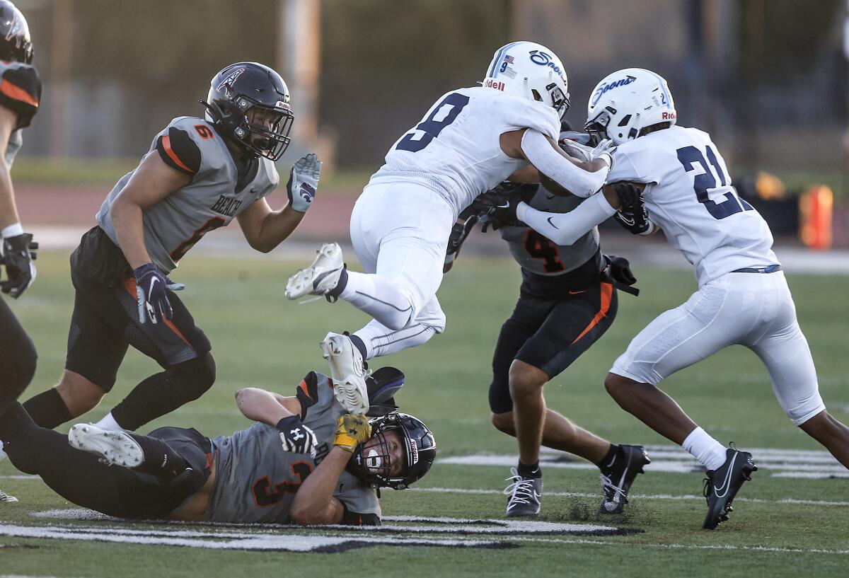 Huntington Beach's Brandon Soleau (3) trips up Mayfair runner Ryan Heredia (9) with Jaxson Brown (6) and Zack James (4).