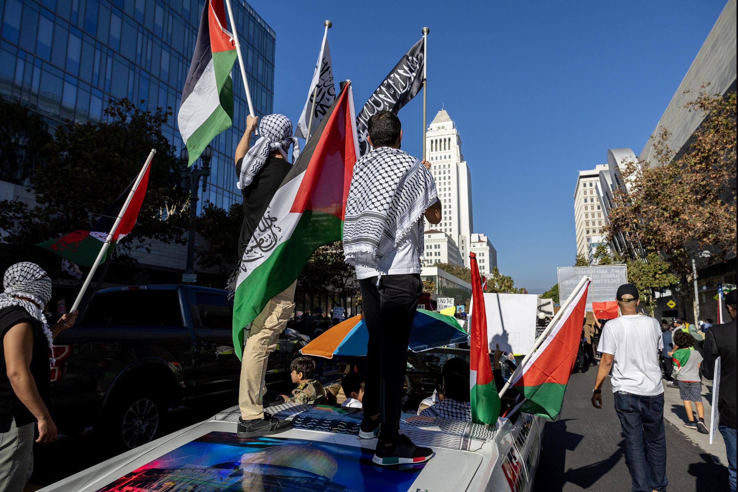 Demonstrators wave Palestinian flags from atop a car during a rally near Los Angeles City Hall.