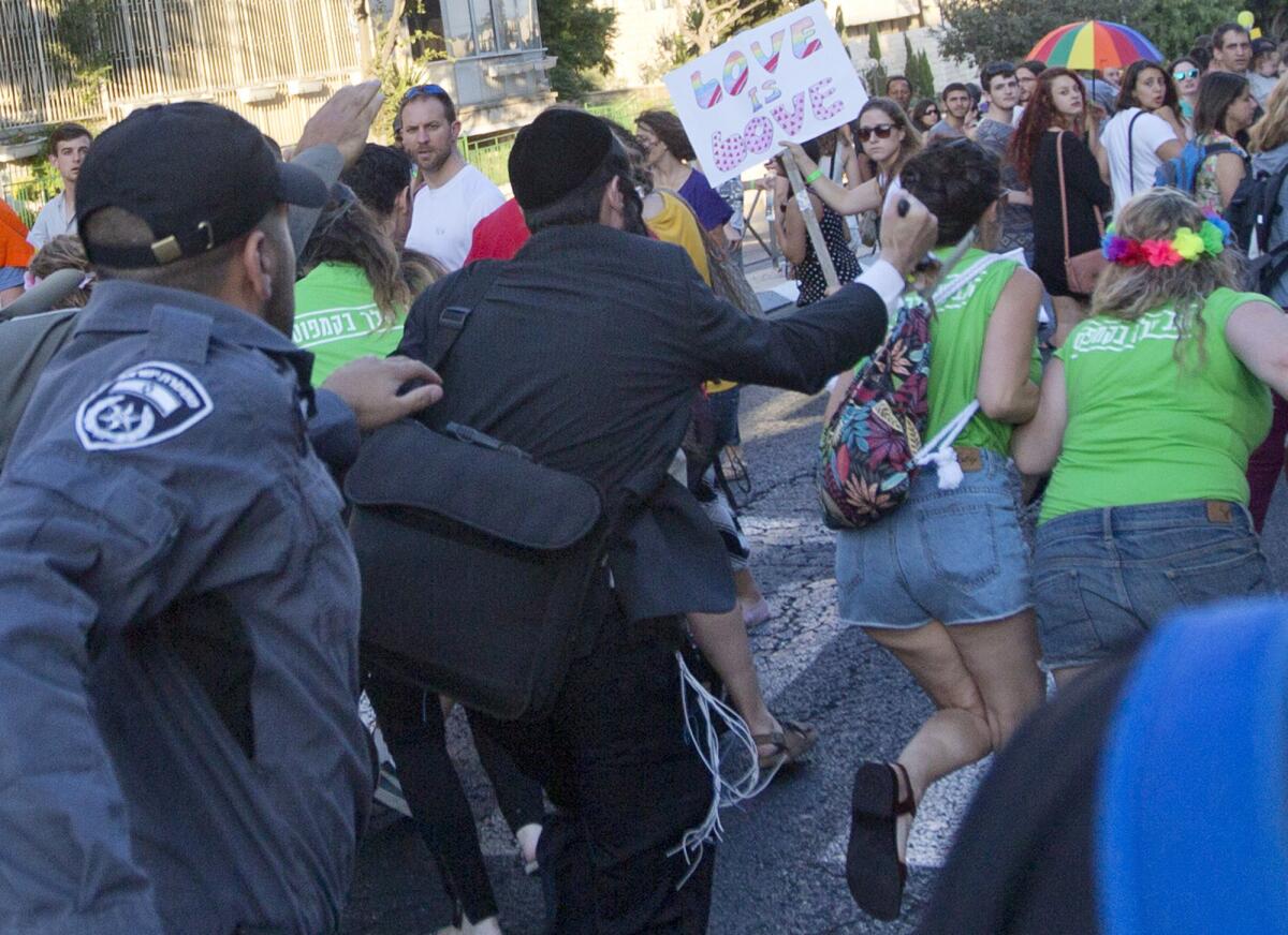 A man later identified as suspect Yishai Shlissel raises a knife at a gay pride parade in central Jerusalem. The girl on the right, with the flowers in her hair, later died of her wounds.