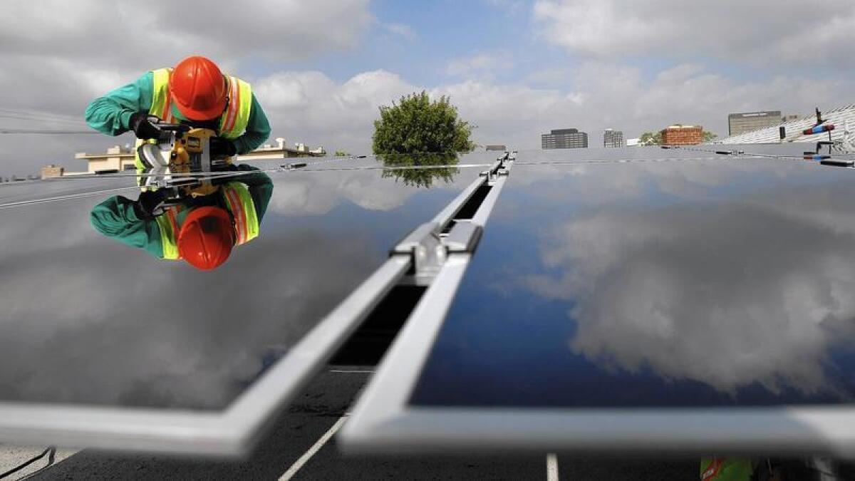 Un instalador de SolarCity coloca paneles solares en una casa en Los Angeles en el 2009.