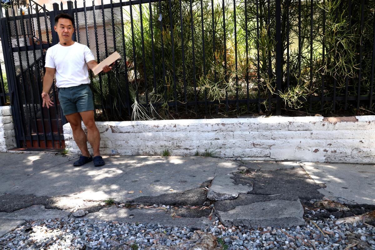     John Yi, 38, looks at a damaged sidewalk along S. Manhattan Place in his Koreatown neighborhood in Los Angeles.