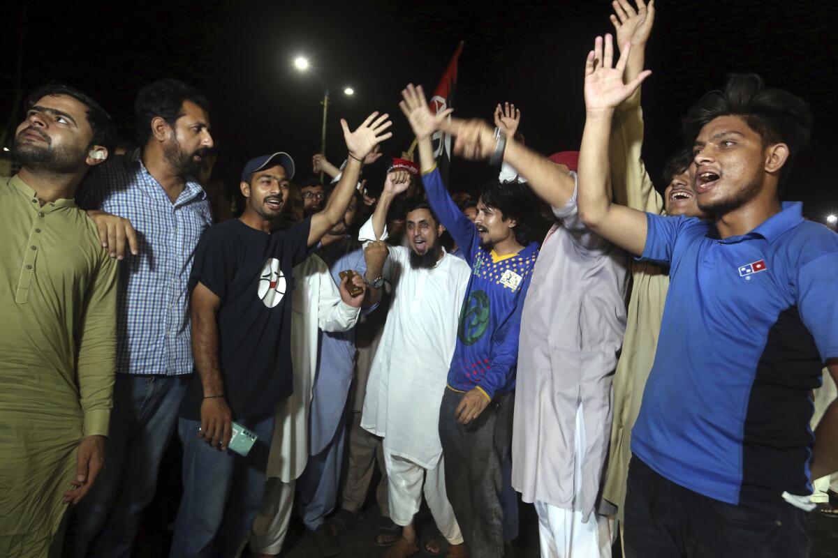 A group of people stand together and raise their hands at night. 