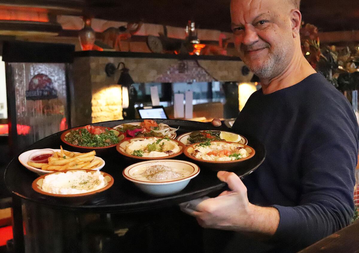 Sam Nordin, owner of the Desert Moon Grill, holds a plater of traditional Middle Eastern mezze. 