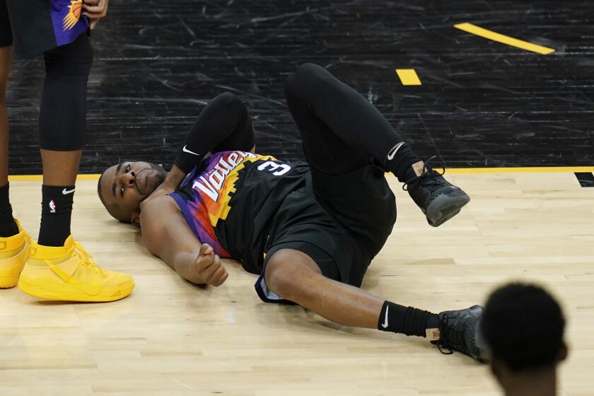 An injured Phoenix Suns guard Chris Paul grabs his shoulder during the first half of Game 1 of their NBA basketball first-round playoff series against the Los Angeles Lakers Sunday, May 23, 2021, in Phoenix. (AP Photo/Ross D. Franklin)