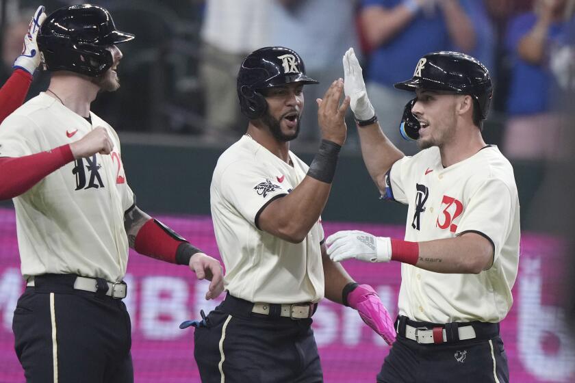 Texas Rangers' Evan Carter, right, celebrates with Jonah Heim, left, and Leody Taveras, who scored on his home run against the Seattle Mariners during the second inning of a baseball game in Arlington, Texas, Friday, Sept. 22, 2023. (AP Photo/LM Otero)