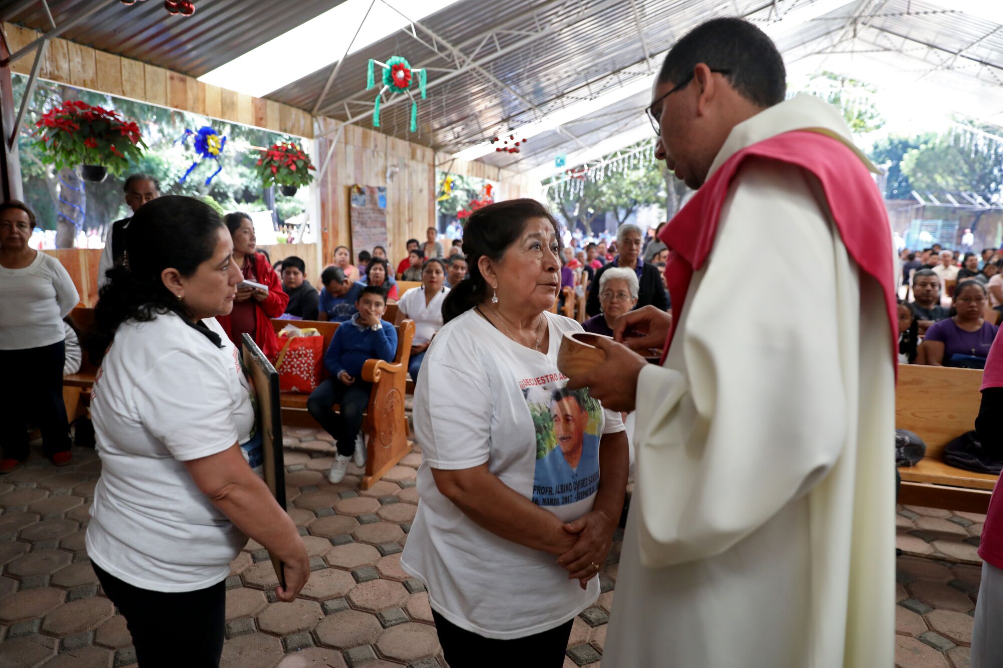 Maricela Peñaloza Flores, center, with daughter Georgina Quiroz Peñaloza, asks the priest if she can make an announcement about her husband in Tepoztlán, Mexico, on Dec. 15.