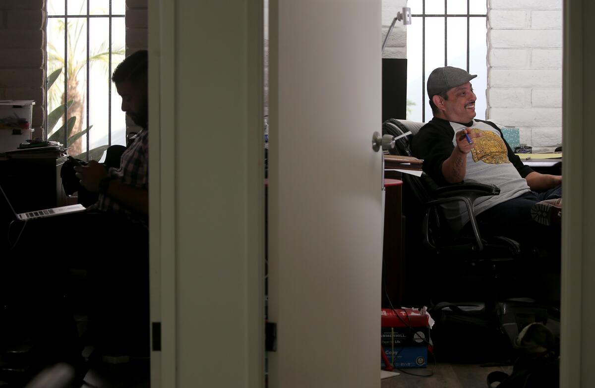 A man sitting at a desk in an office as seen through an open door