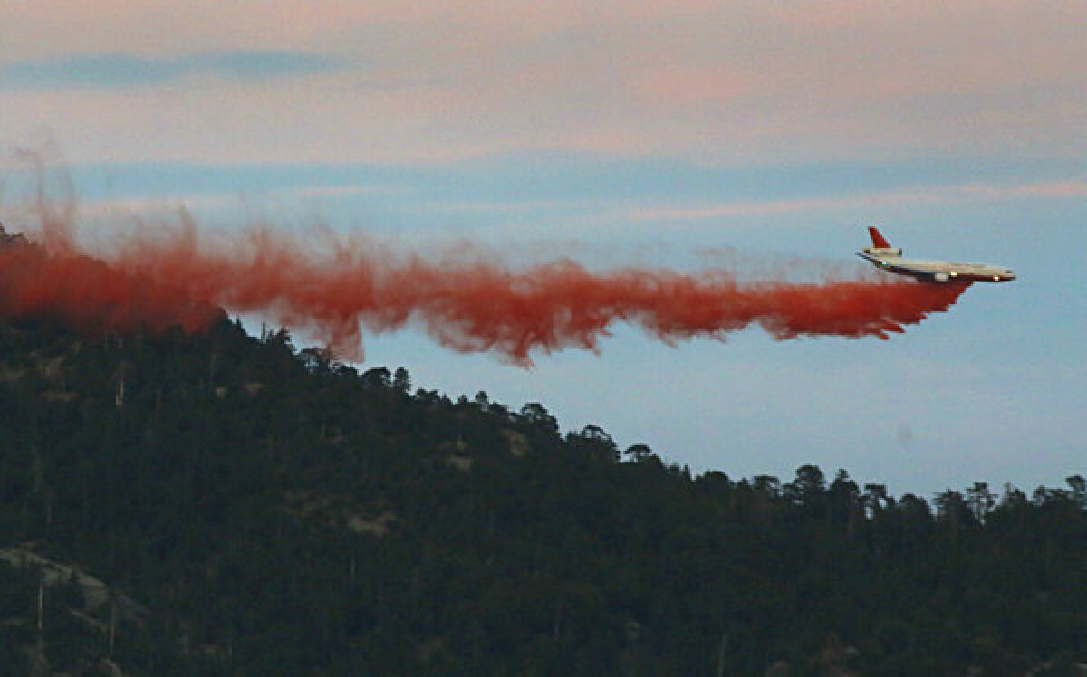 As the sun sets Friday, a DC-10 supertanker makes its final drop of fire retardant over a ridge a few miles from Idyllwild.