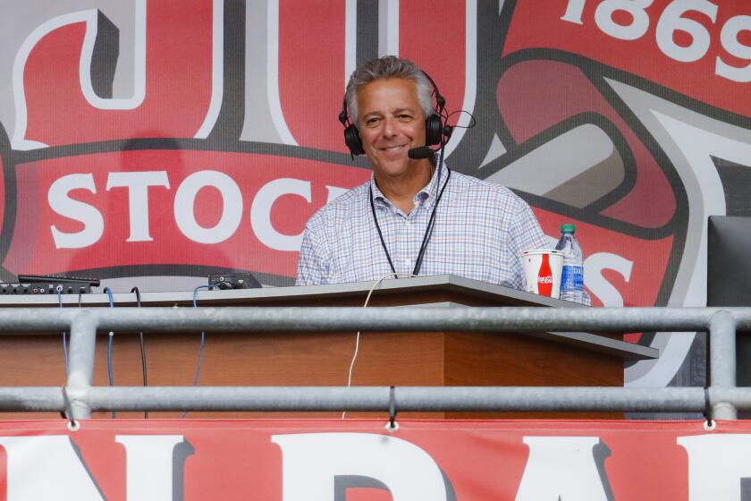 Cincinnati Reds radio announcer Marty Brennaman, left, waves next to his son Thom.
