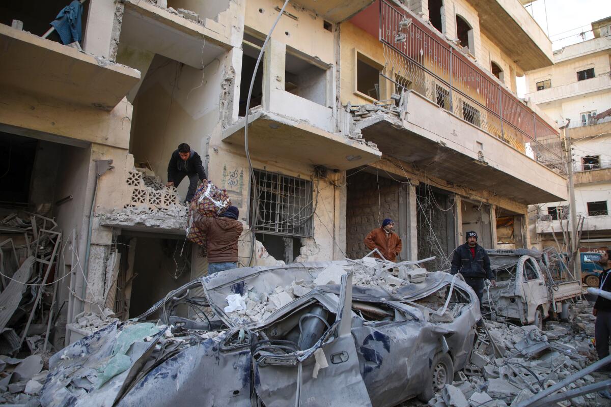 Syrians gather their belongings Jan. 30 following reported airstrikes in the town of Ariha.