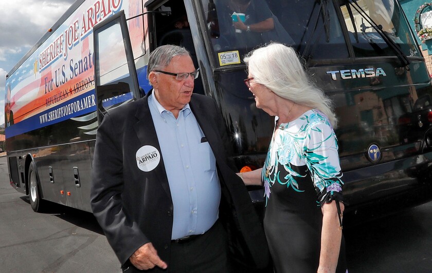Former Maricopa County Sheriff Joe Arpaio and his wife, Ava, next to a campaign bus.