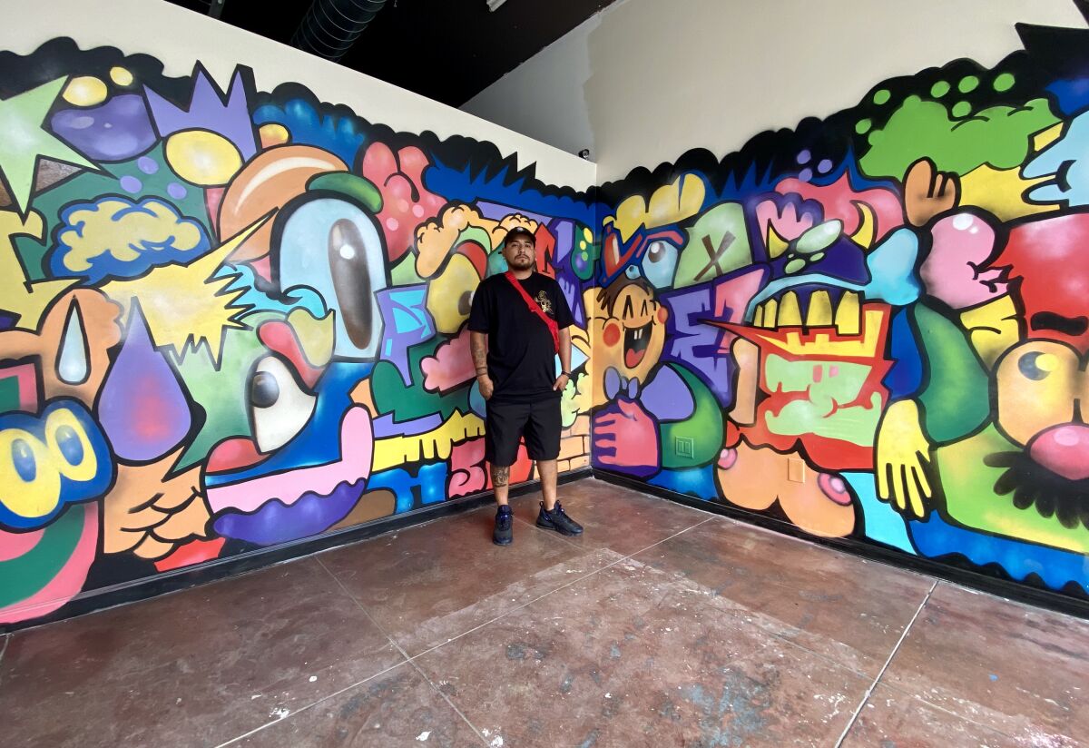 Juan Carlos Galindo poses next to his mural in the Front Gallery