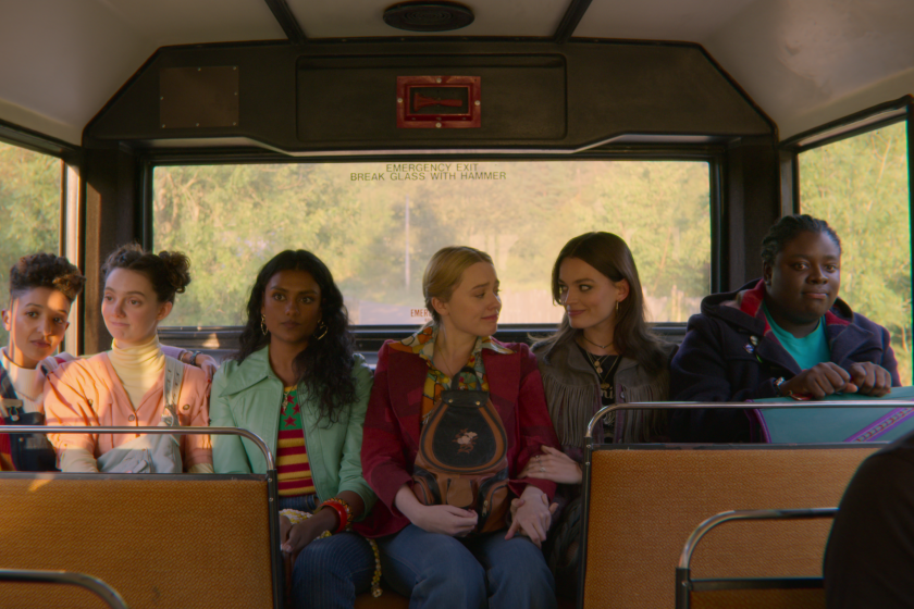 Six girls sitting in a row in the back of a public bus