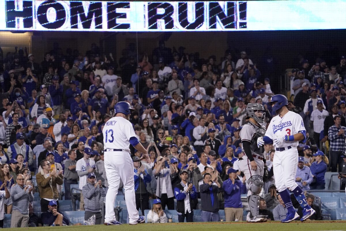 Los Angeles Dodgers designated hitter Chris Taylor, right, celebrates with Max Muncy, left, after hitting a two-run home run as Arizona Diamondbacks catcher Jose Herrera stands at the plate during the sixth inning of a baseball game Monday, May 16, 2022, in Los Angeles. (AP Photo/Mark J. Terrill)