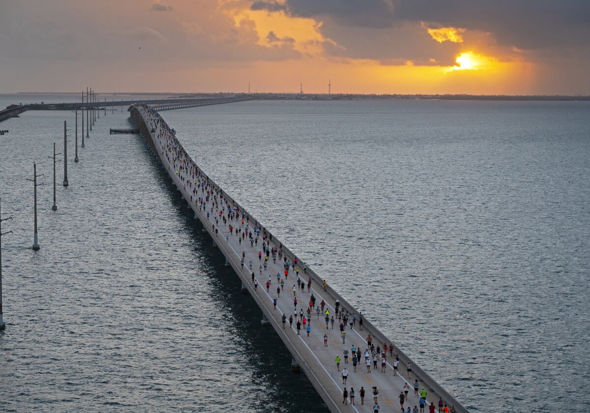 In this photo provided by the Florida Keys News Bureau, the sun rises above the Atlantic Ocean in the Florida Keys as a field of 1,500 competitors traverses the Seven Mile Bridge from Little Duck Key to Marathon, Fla., Saturday, April 1, 2023. The annual Seven Mile Bridge Run shut down the longest bridge on the Florida Keys Overseas Highway to traffic for three hours Saturday morning for the race over the convergence of the Atlantic Ocean and Gulf of Mexico. Joanna Stephens, 28, of Atlanta won the overall women's title and Vaclav Bursa, 15, of Big Pine Key, Fla., won the overall men's division. (Andy Newman/Florida Keys News Bureau via AP)
