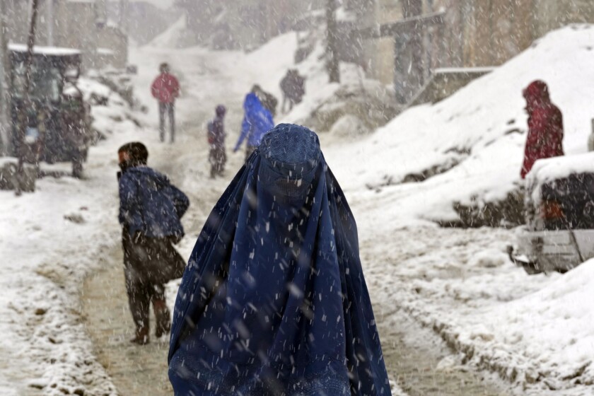 People navigate a snow covered street on a hilltop in Kabul, Afghanistan, Tuesday, Feb. 22, 2022. (AP Photo/Hussein Malla)