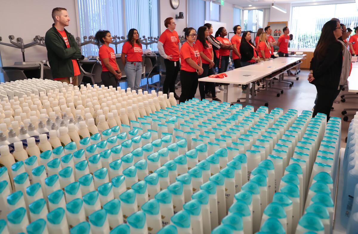 Johnson & Johnson MedTech volunteers listen to project instructions near a hundred bottles of hair product.