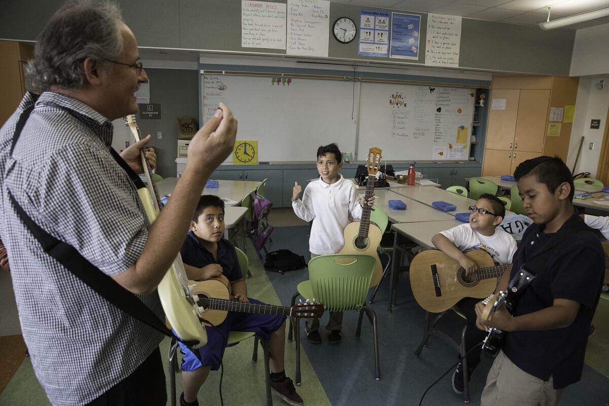Rock band director Raymond Little, left, conducts practice with students at Carlos Santana Arts Academy in North Hills, Calif. (Brian van der Brug / Los Angeles Times)