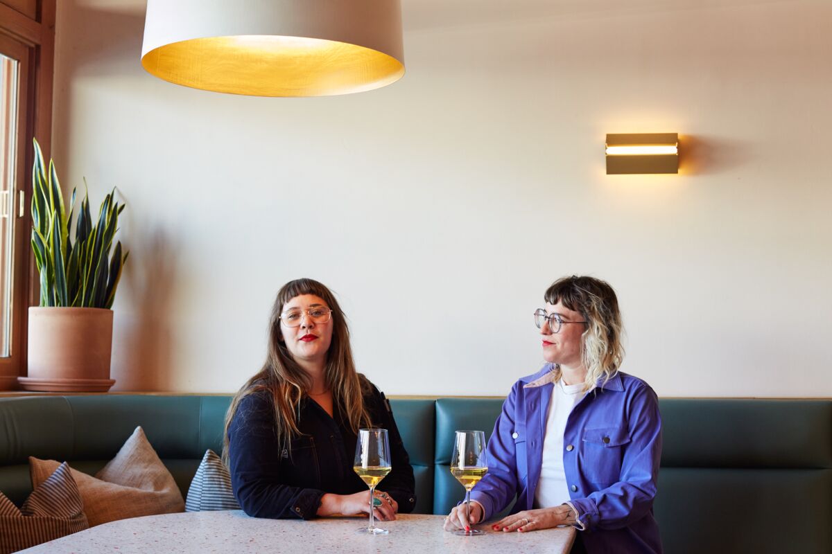 two women sit at a table in a restaurant with wine glasses