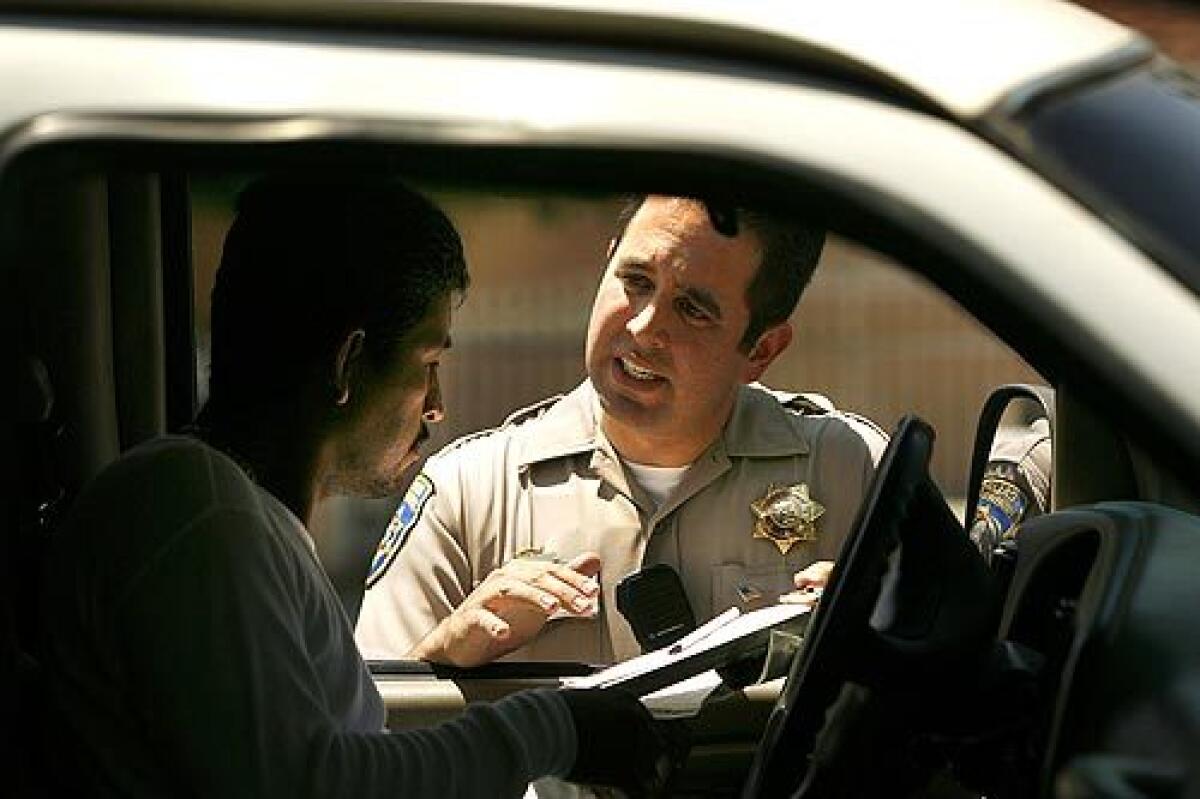 California Highway Patrol public affairs officer Joe Zizi tickets one of several drivers he caught using their cellphones without a hands-free device, violating a law that just took effect.