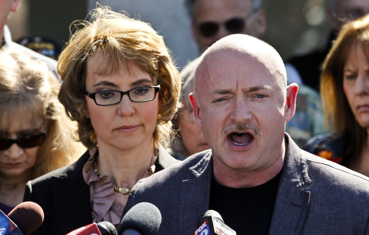 Former Rep. Gabrielle Giffords stands beside her husband, former astronaut Mark Kelly, during a return to the supermarket where she was wounded in a shooting rampage two years ago in Tucson, Ariz.