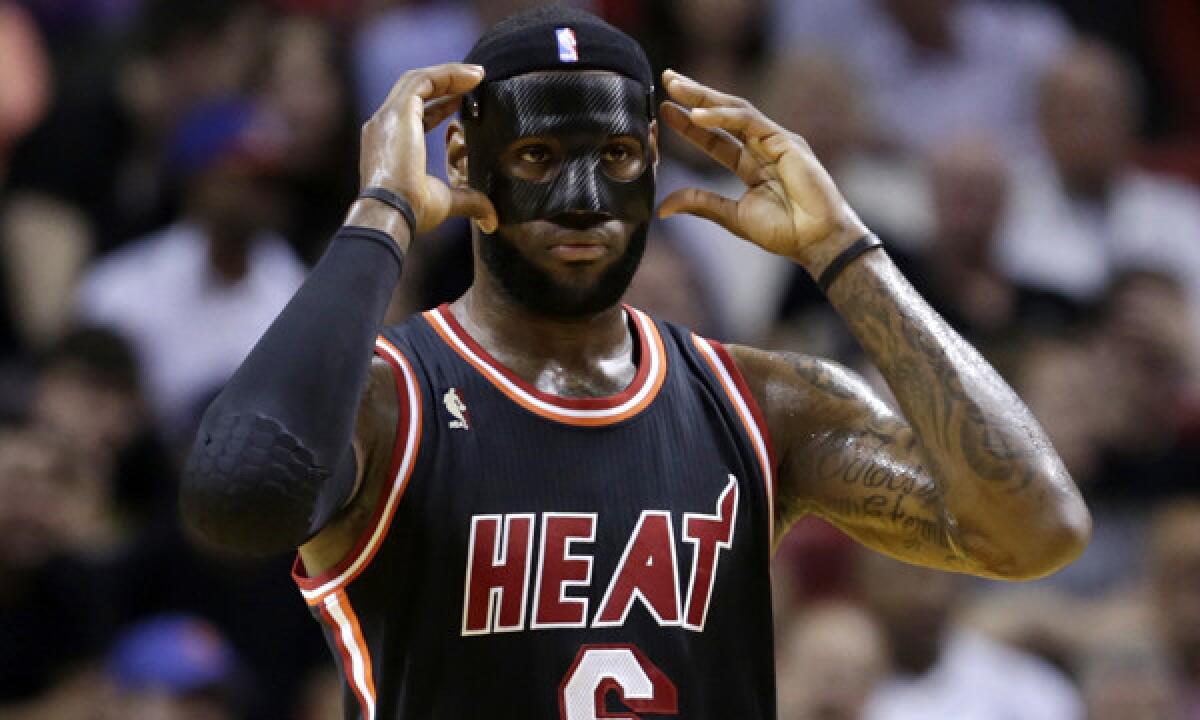 Miami Heat star LeBron James adjusts his protective mask during the first half of Thursday's game against the New York Knicks.