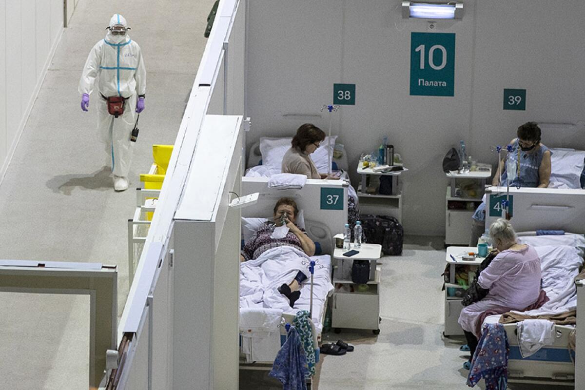 A medical worker walks near a room of four coronavirus patients at a temporary hospital in Moscow.