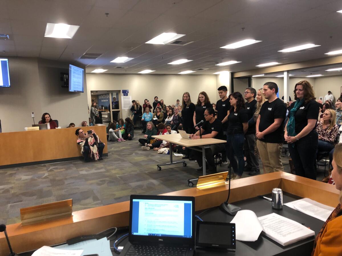 Members of Huntington Beach City School District music staff flank Dwyer Middle School music teacher Neil Reyes on Tuesday night while he addressed the board of trustees about the impact of music programming on his students and implored them to prevent deep program cuts.