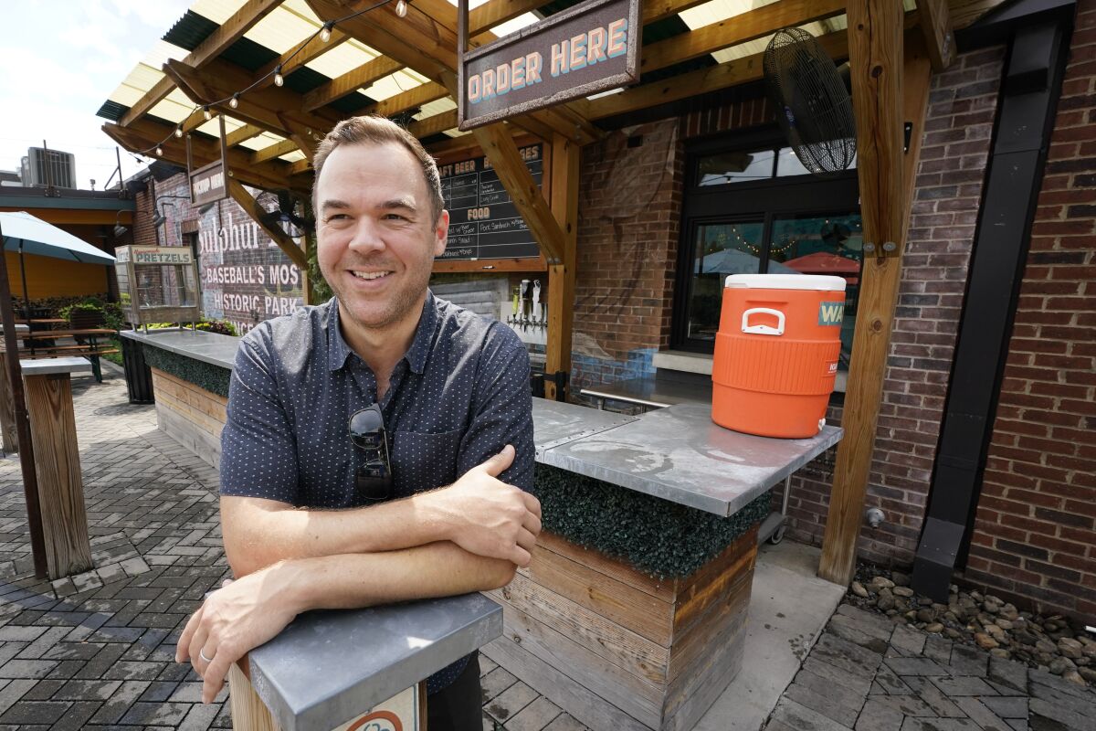 Austin Ray, owner of Von Elrod's Beer Hall And Kitchen, stands in the restaurant's outdoor seating area June 7, 2022, in Nashville, Tenn. For the restaurant, located across the street from Nashville's minor league baseball stadium that sees big crowds in the summer, both inflation and the worker shortage have sent costs skyrocketing. Small businesses that depend on summer crowds and tourism are hoping for a bustling summer this year, boosted by pent up demand after more than two years of the pandemic. (AP Photo/Mark Humphrey)