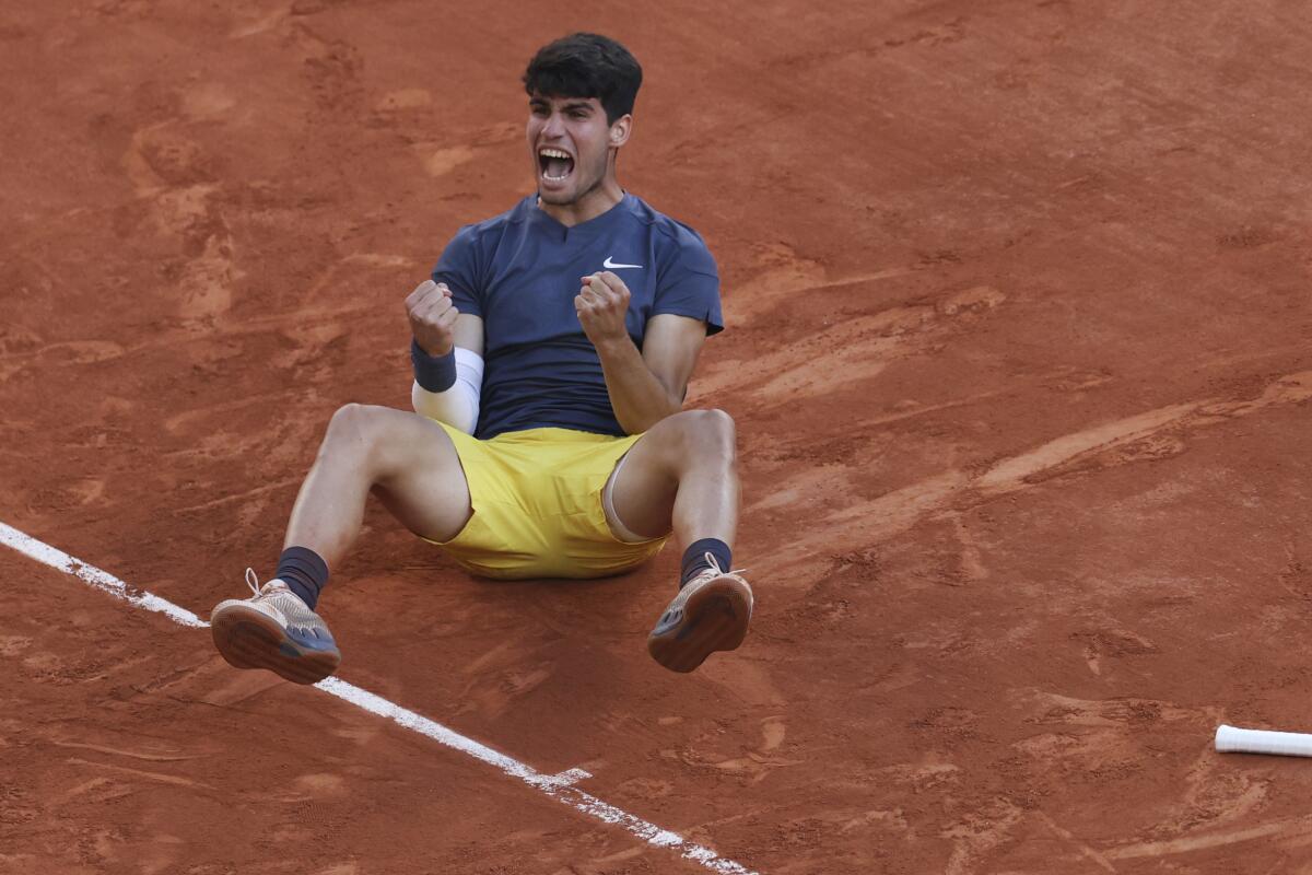 Carlos Alcaraz falls to the clay court as he celebrates winning the French Open on Sunday in Paris.