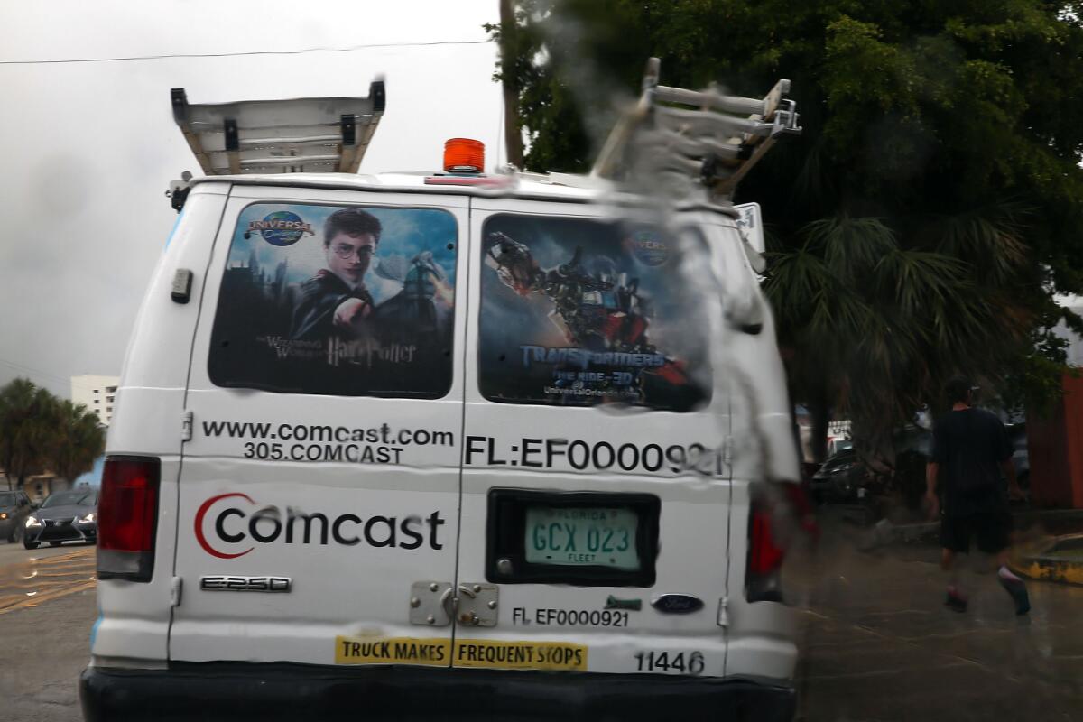 A Comcast service van is seen through a rain soaked windshield on Thursday in Miami.