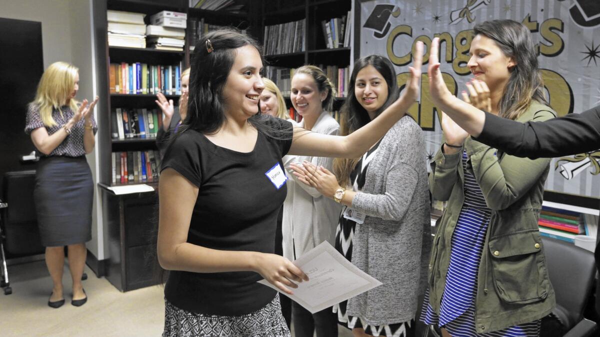 Monica Romero high-fives volunteers during her graduation ceremony from a 16-week course held at UCLA that helps young adults with autism build social skills.