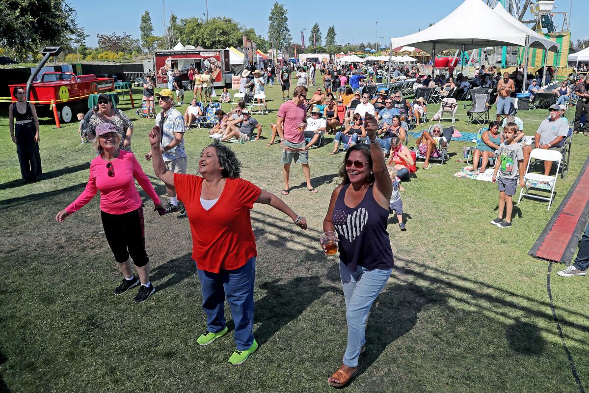 Festival-goers dance as Flashback Heart Attack performs live during Summerfest at Fountain Valley Sports Park on Saturday.