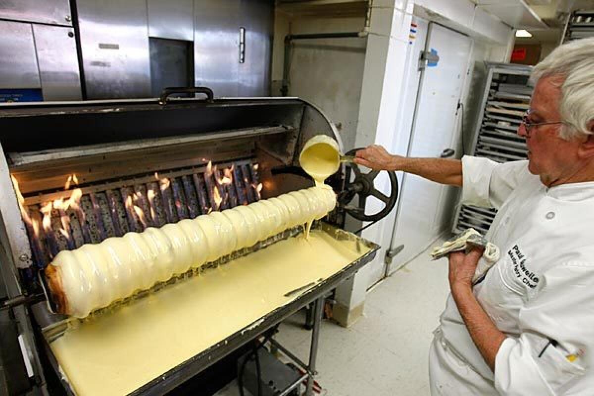 Paul Gauweiler ladles batter on the spindle of his baumkuchen machine at his Huntington Beach bakery. It's one of the few such ovens in the U.S.