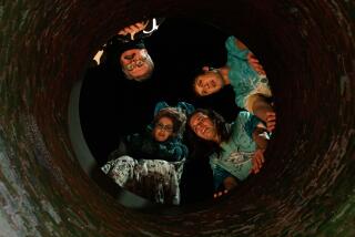 Two parents and their grown sons peer down a manhole into the sewer at night in "Dicks: The Musical."